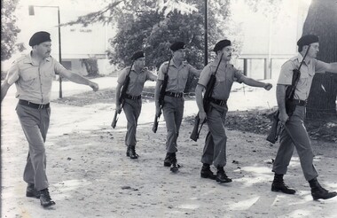 Fiver soldiers marching, trees in background.