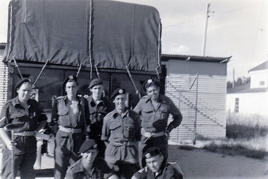 Group of soldiers standing behind truck