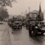 Army vehicles in street on rainy day.