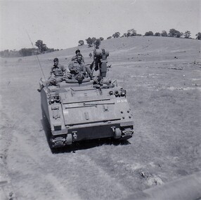 Soldiers riding on top of vehicle with tracks