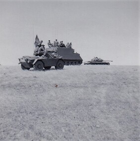 Soldiers sitting on top of armoured vehicles