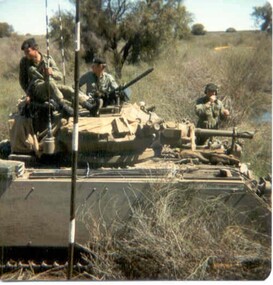 Three soldiers wearing berets sitting on top of a tank