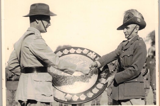 Two army officers with a large dish shaped trophy.