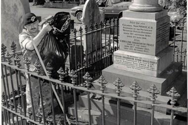 Soldier removing bag of leaves around grave headstone