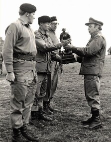 Three soldiers receiving trophy from officer