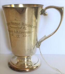 A silver drinking mug with engraving on side.