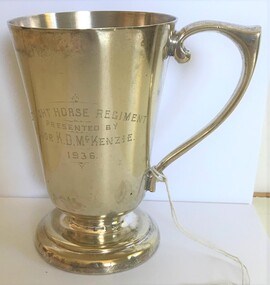 A silver drinking cup with engraving on side.