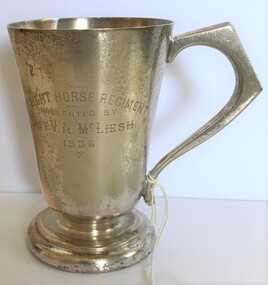 A silver drinking cup with engraving on side.