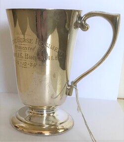 A silver drinking cup with engraving on side.