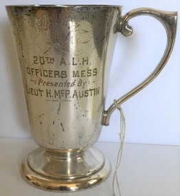 A silver drinking cup with handle and engraving on side.
