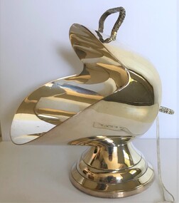 A silver scoop shaped bowl with handle on top