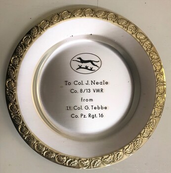 A metal disk with decorative rim and engraving in centre.
