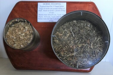 Two tins with plastic lids filled with grain and chaff and attached to a board
