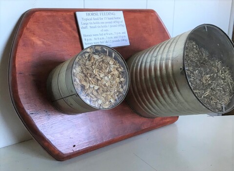 Two tins filled with grain and chaff attached to a board