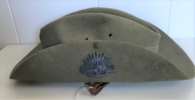 Felt hat with one side of brim turned up and held by a badge.