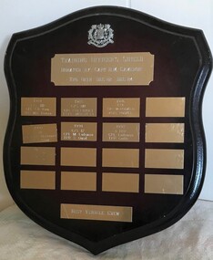 Wooden shield with plates with writing attached to it.