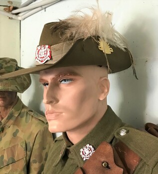 Portrait of mannequin wearing hat with plumes on side of brim.