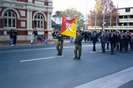 Men marching in city street behind banner