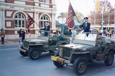 Two Jeeps with men standing with flags.