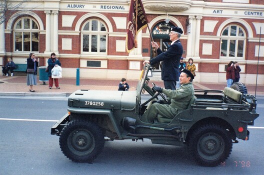 Jeep in main street, man with flag.