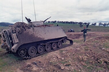 Soldier standing in front of and directing tank