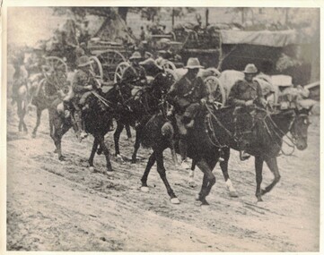 Soldiers on horses riding past a wagon