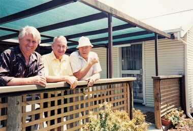 Three men leaning on verandah rail