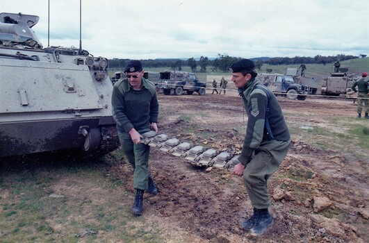 Two soldiers carrying heavy object.