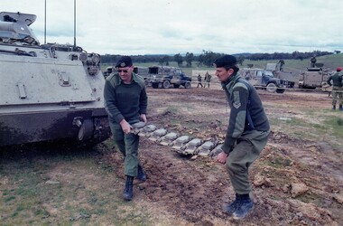 Two soldiers carrying heavy object.