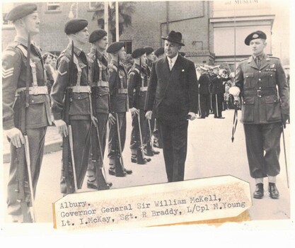 Man in suit and hat with soldiers