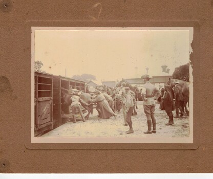 Soldiers pushing horses into stalls on train.