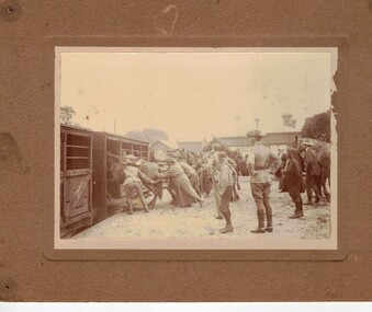 Soldiers pushing horses into stalls on train.