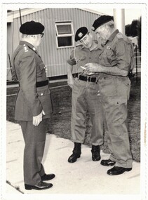 Three men in army uniform near hut