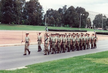 Soldiers with rifles marching on road