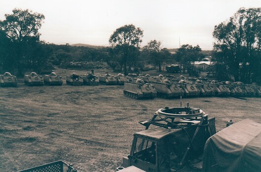 Large line up of army tracked vehicles.