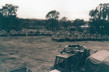 Large line up of army tracked vehicles.