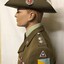 Mannequin wearing hat with badge and plumes.