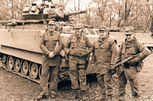 Four soldiers wearing caps near tank