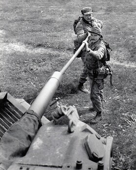 Two soldiers cleaning tank gun.