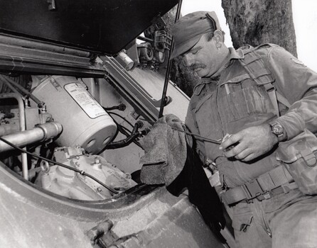 Soldier checks oil in vehicle