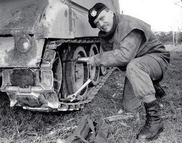 Soldier kneeling beside vehiicle with tracks
