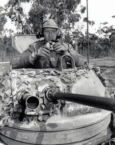 Soldier with binoculars in turret of tank