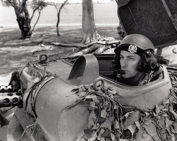 Soldier wearing helmet and beret in tank