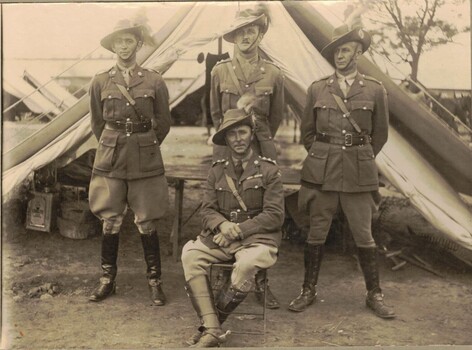 Four soldiers in front of tent.