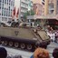 Tank in street, carrying soldiers with flags