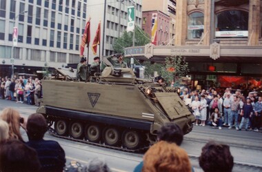 Tank in street, carrying soldiers with flags