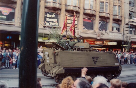 Tracked vehicle carrying soldiers with flags