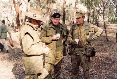 Three soldier talking; all have different hats.