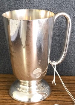 Silver drinking mug with handle, engraved on side.