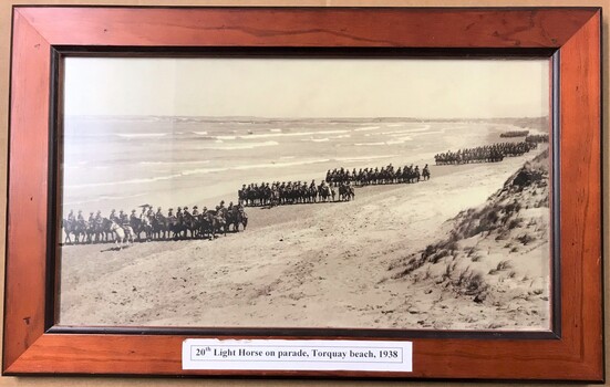 Framed photograph of lines of horsemen on beach.